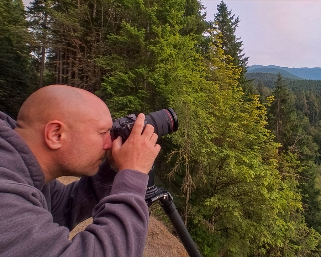 Tom Buscher photographing a forested mountain overlook at dusk